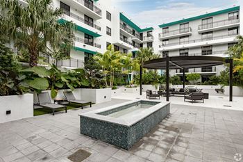 Serenity garden with lounge seating and a pergola in the background at Hollywood Heights on the Boulevard Luxury Apartments in Hollywood, FL